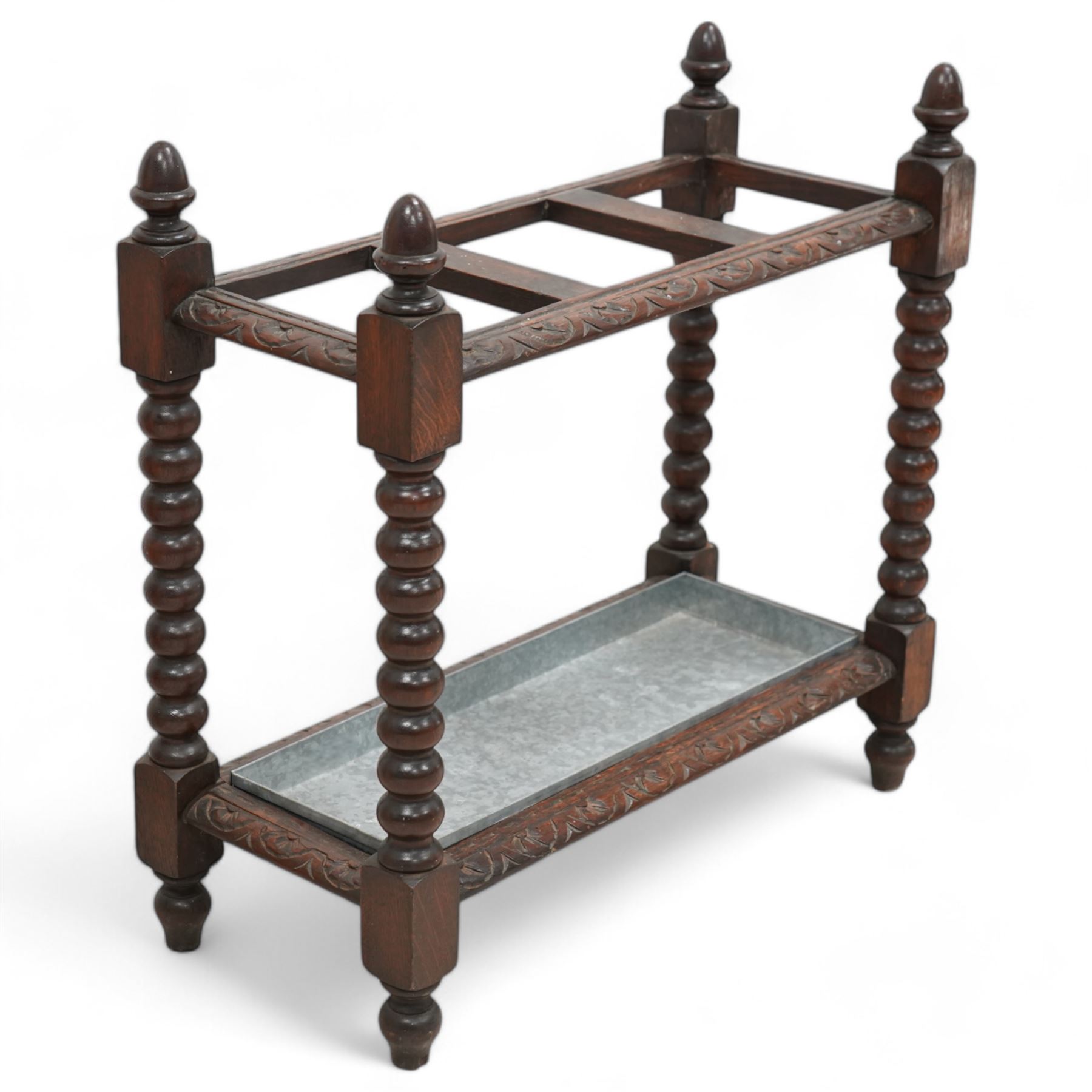 Victorian carved oak stick stand, three divisions within lunette carved frame, on bobbin turned supports united by carved stretchers, with drip tray 