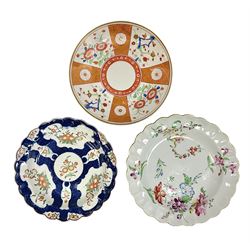 Three 18th century Worcester desert dishes, the first example decorated in the Scarlet Japan pattern, circa 1790, painted with alternating panels of Kakiemon style prunus blossom and chrysanthemum, and orange ground panels with gilt fret detail, D19cm, the second example, circa 1770, decorated with Kakiemon style chrysanthemums and foliage within shaped reserves upon a blue scale ground, with fretted square pseudo mark beneath, D19cm, and the third, circa 1770, painted with polychrome floral sprays and sprigs, D20cm