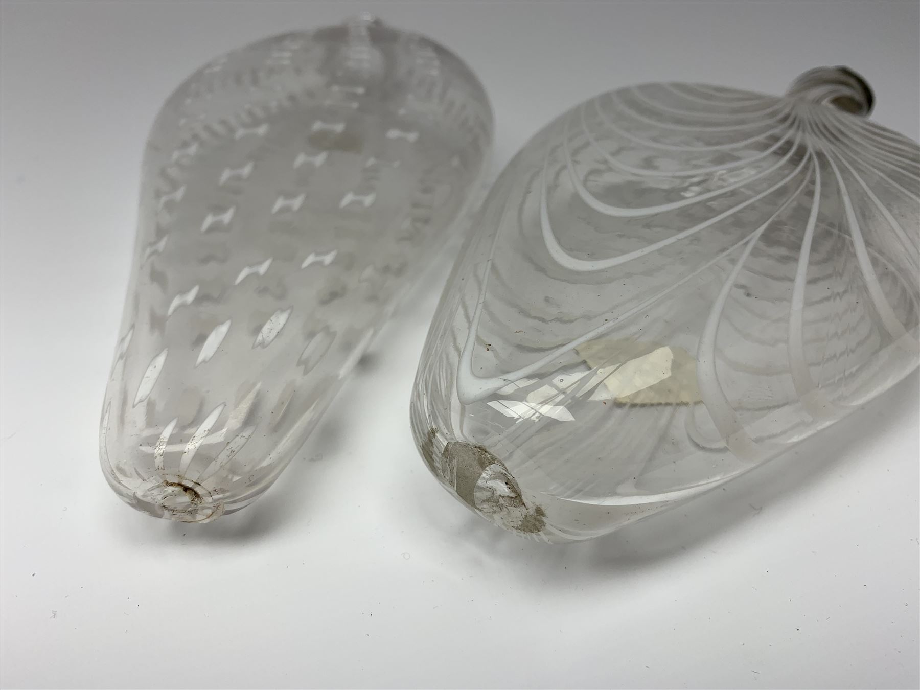 19th century Nailsea glass flask of compressed ovoid form, the clear body with opaque white combed decoration, H21cm, together with another similar example decorated with enamelled stylised bands, H23cm