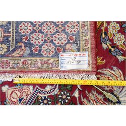 Central Persian Najafabad hand-knotted carpet, crimson field with a central elaborate cusped medallion with radiating floral motifs, surrounded by finely drawn scrolling vines incorporating stylized palmettes and rosettes, flowering plants and vase motifs, ivory spandrels similarly decorated enclosed by a dark indigo main border of floral arabesques between multiple guard stripes, with cotton fringe ends 