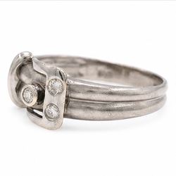 14ct white gold three stone diamond buckle ring, bezel and rubover set with three round brilliant cut diamonds, to a brushed and polished gold band, stamped 585