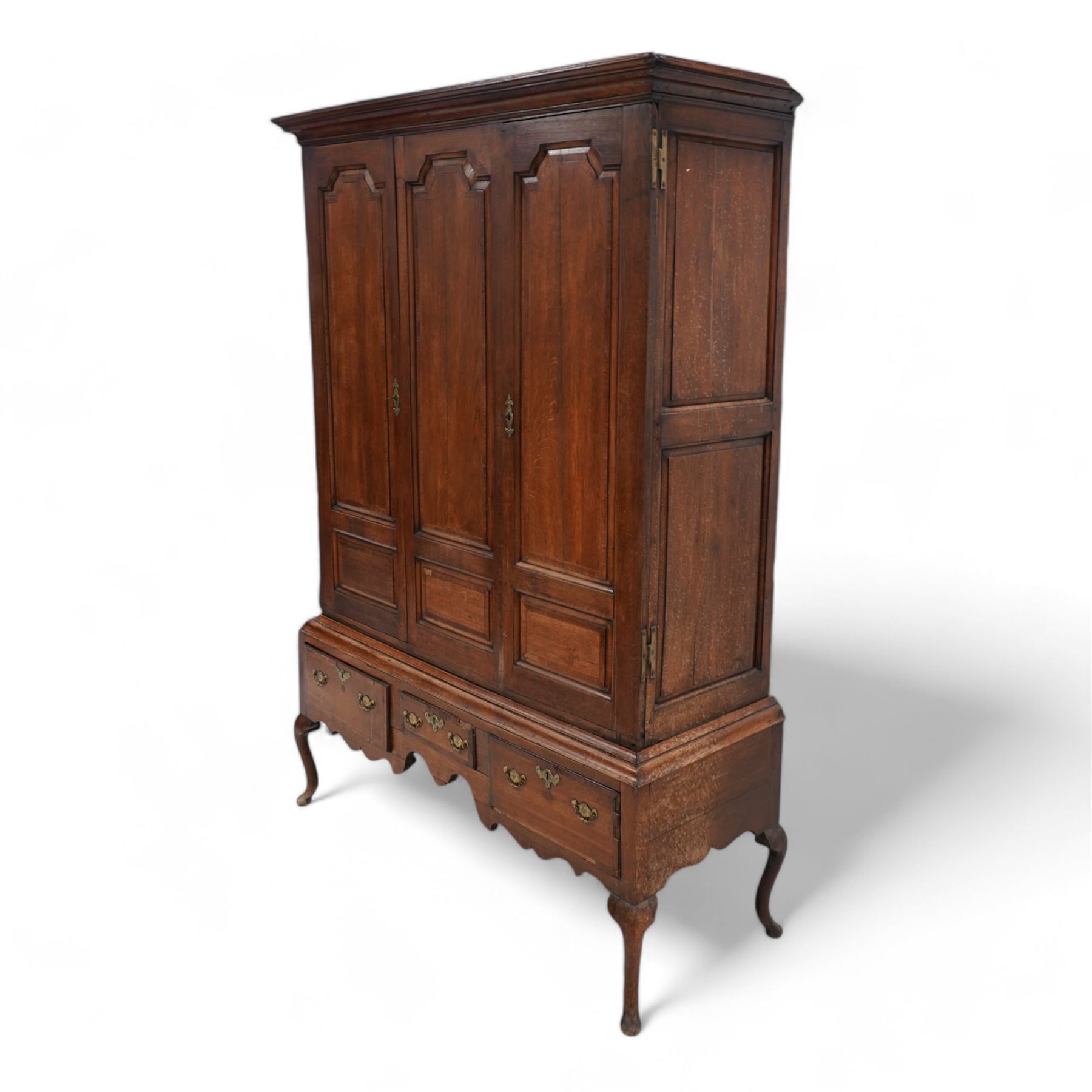 Georgian oak livery cupboard, projecting cornice over panelled front with mahogany bandings, enclosed by two doors, the base fitted with three drawers over shaped apron and cabriole supports 