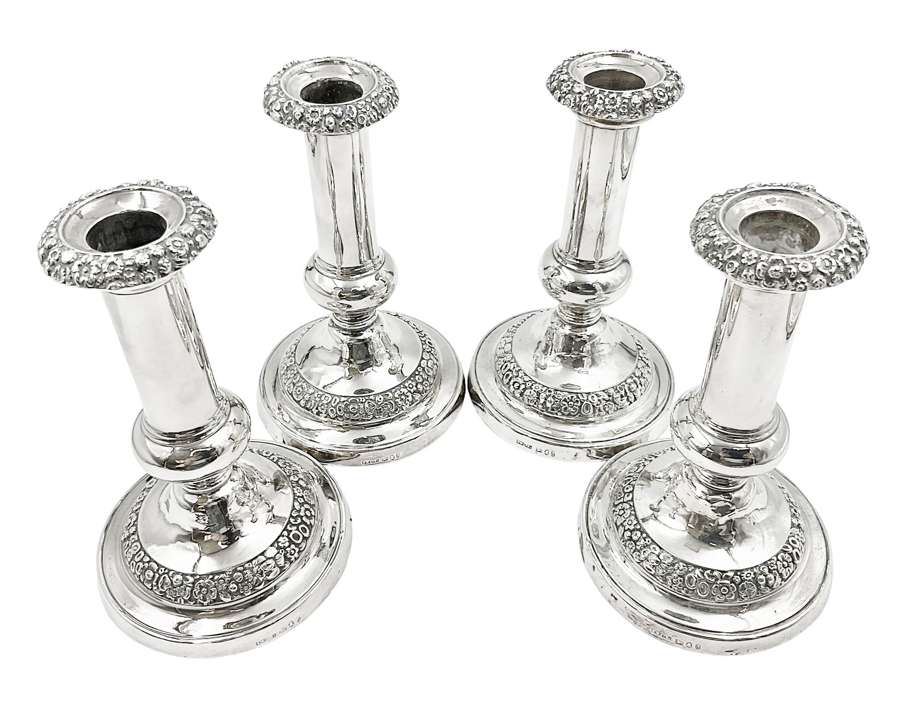 Four George III silver candlesticks, each upon knopped stem and weighted circular stepped foot, the foot and removable sconce repousse decorated with a band of flower heads, hallmarked to sconce and foot Thomas & John Settle, Sheffield 1820, H17.5cm