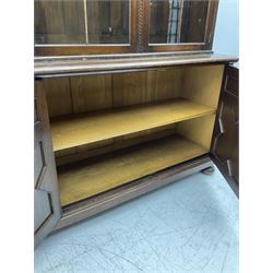 Waring and Gillow - oak bookcase on cupboard, projecting cornice over arcade frieze, guilloche upright decoration, the top section enclosed by three astragal glazed doors, the lower section enclosed by three geometric panelled doors with blind fretwork decoration, on turned feet