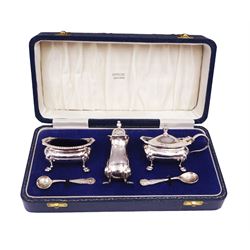 Modern silver three piece cruet set, comprising pepper shaker, open salt and mustard pot with cover, each with oblique gadrooned rim, palmette corners and upon four paw feet, with two matching spoons, hallmarked William Suckling Ltd, Birmingham 1992, the mustard pot and salt with blue glass liners, all contained within tooled leather silk and velvet lined fitted case, stamped Harrods London to interior silk lining