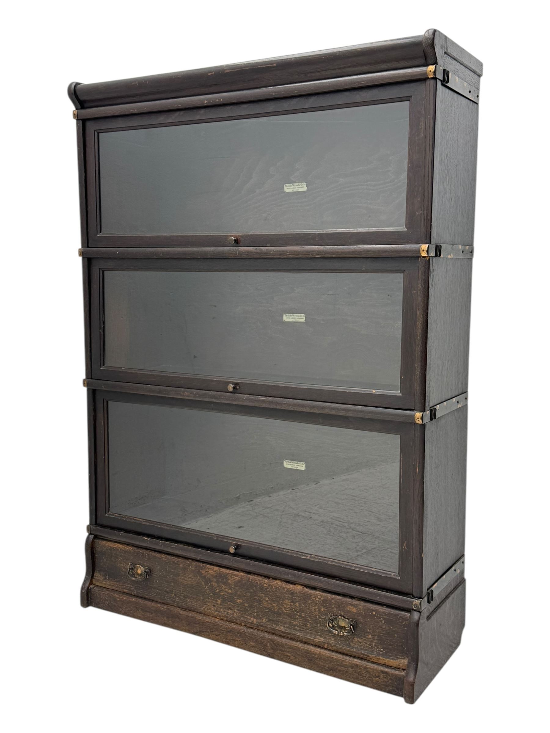 Globe Wernicke - early 20th century oak three-tier stacking library bookcase, three glazed sections enclosed by hinged and sliding doors, raised above a single lower drawer with metal drop handles