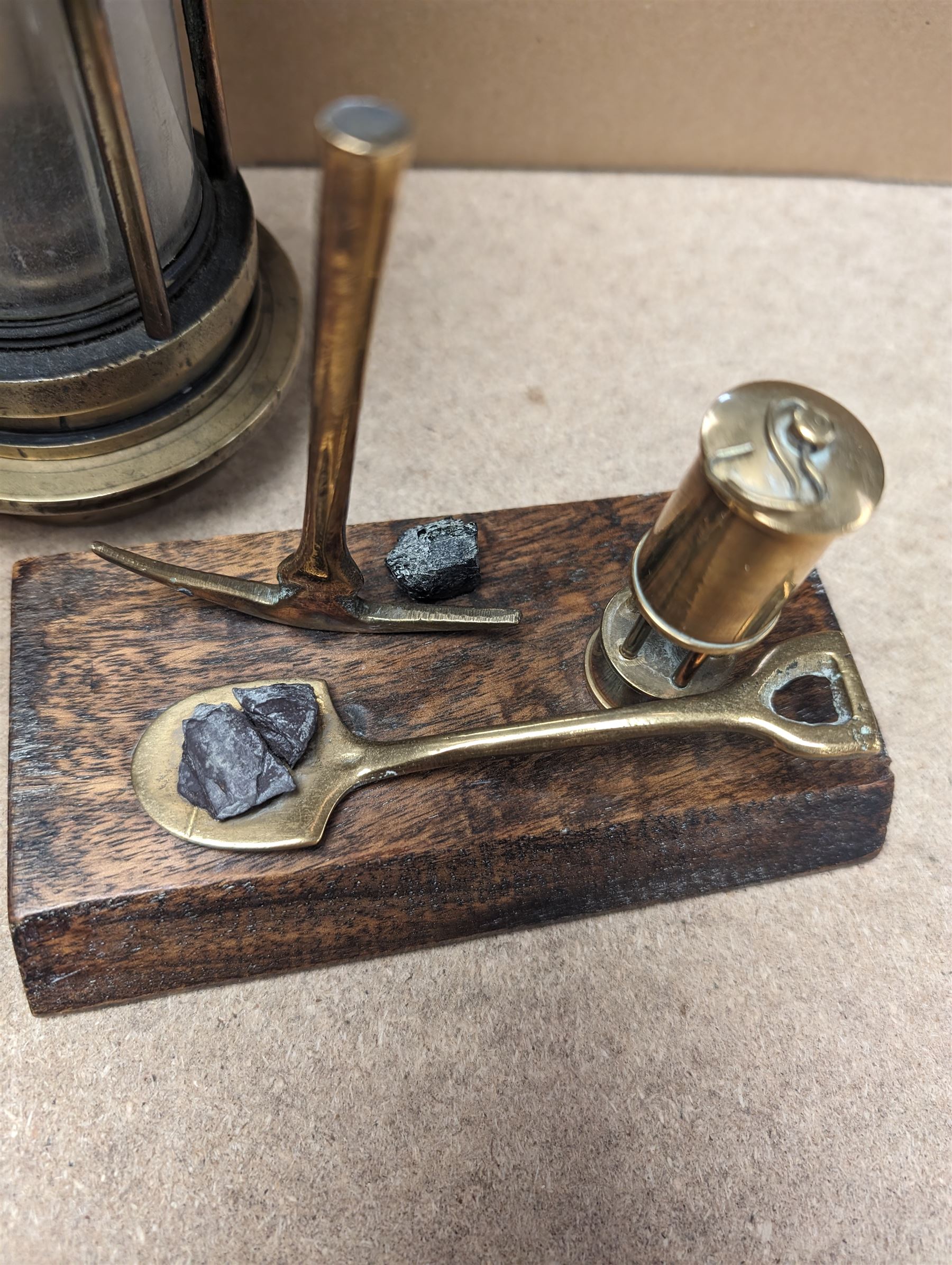 Miners lamp, with plaque numbered 173, together with a miniature brass miners lamp and a wooden paperweight with applied brass miners lamp, pick axe and shovel