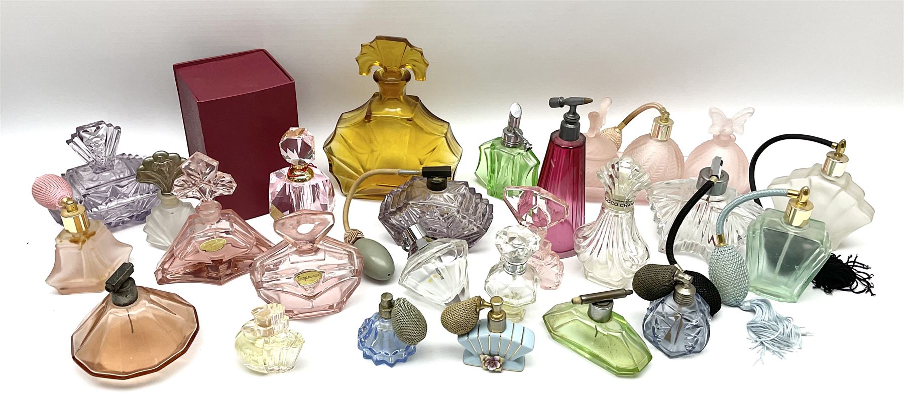 Art Deco style glass perfume bottles and atomisers, to include a large amber example with stopper of fan shape, H18cm, green glass examples with metal stoppers, and a number of other Art Deco style coloured bottles of geometric form with stoppers and mounts