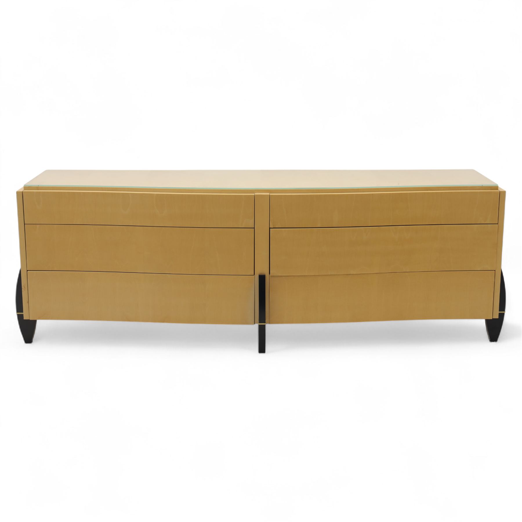 Contemporary maple veneered sideboard, serpentine glass top over six graduating Blum soft-close drawers, raised on curved black and gilt accented supports