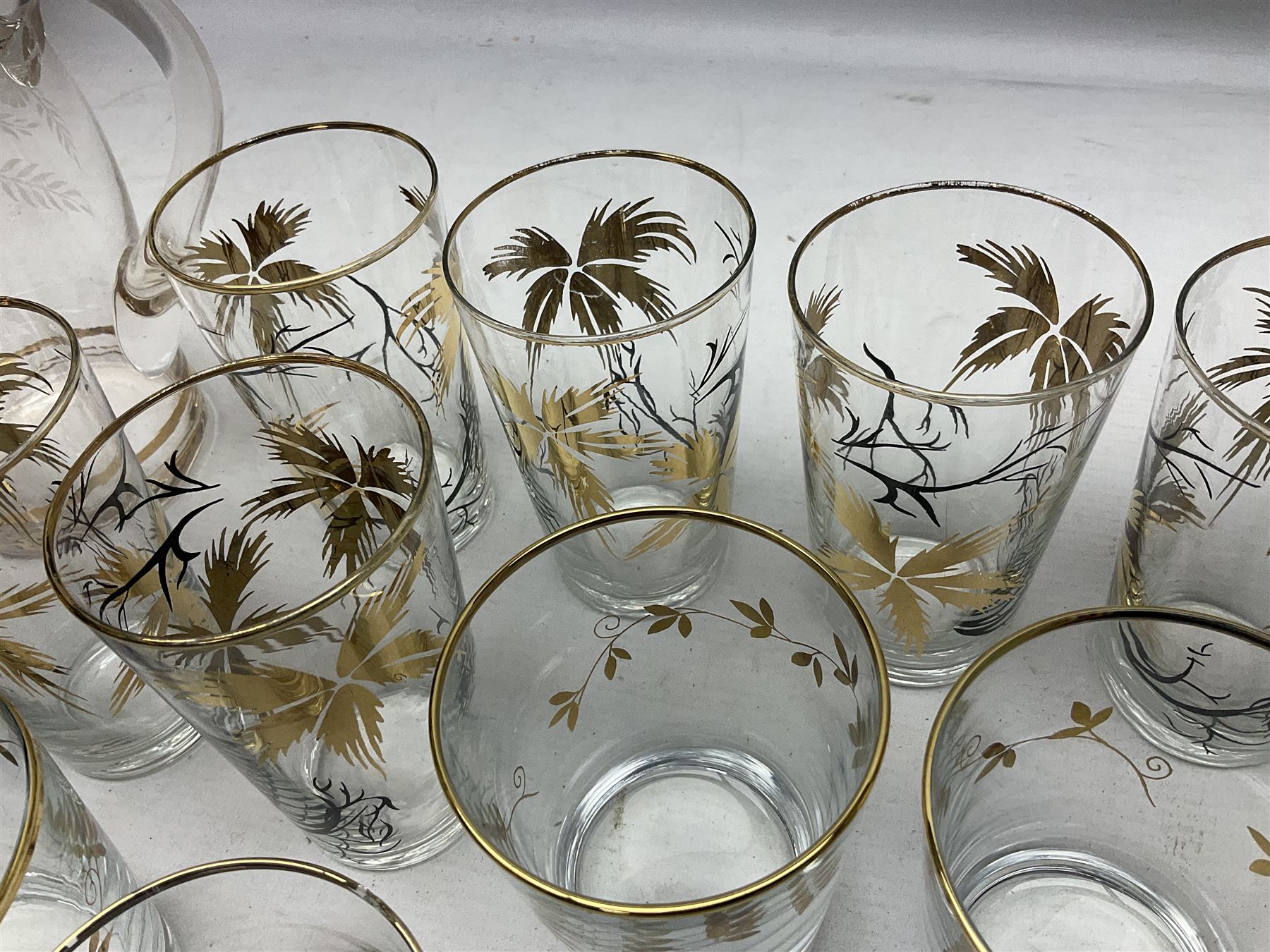 Mid 20th century glass part lemonade set comprisimg jug decorated with white floral sprays and gilt banding with three matching cups, together with a set of six tumblers decorated in black and gilt with flowers and set of four other glasses