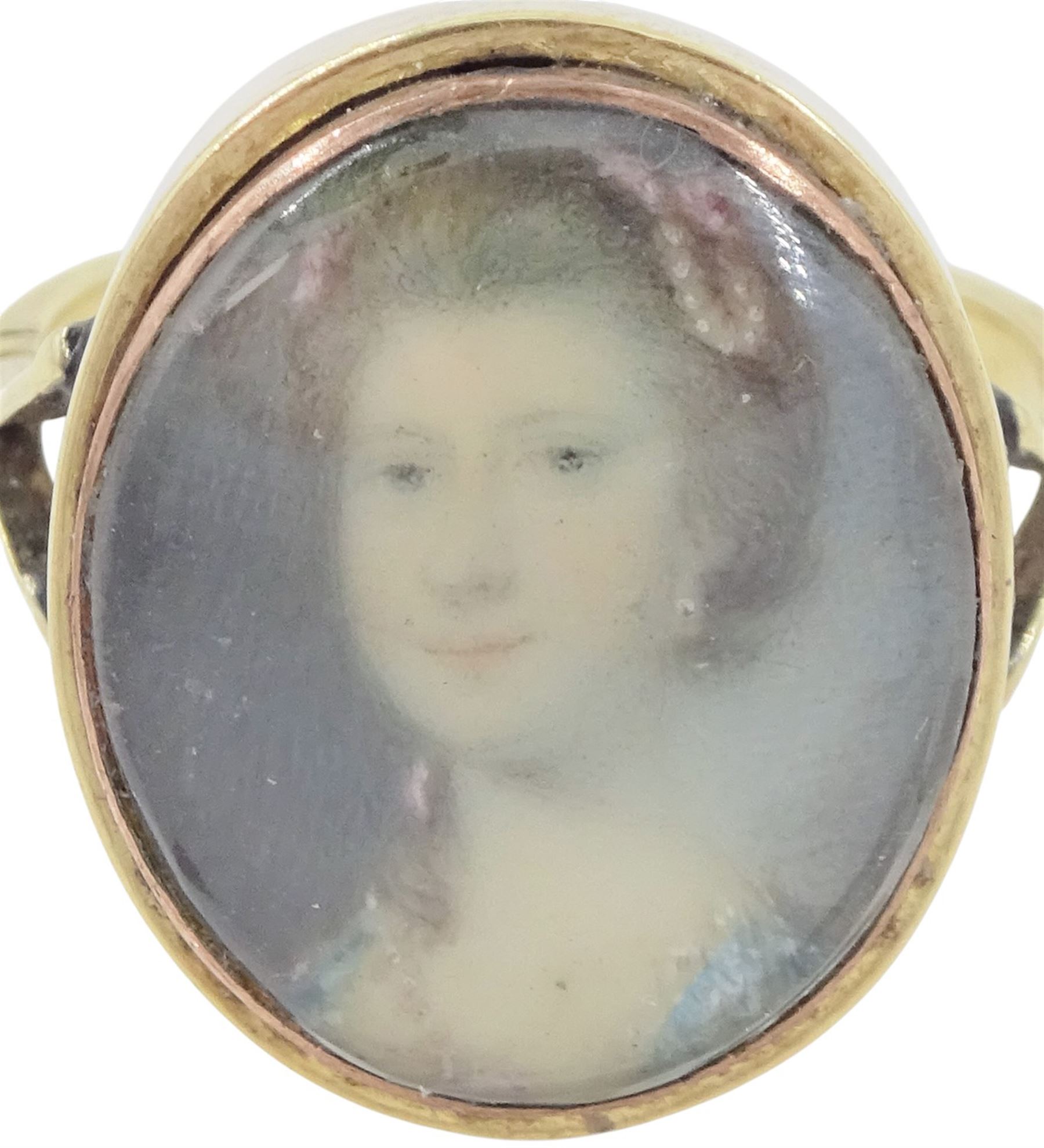 19th century gold portrait ring, set with an oval miniature of a woman wearing a pearl hairpin and earrings on ivory, under a glazed panel, set into a later gold ring with split shoulders. This lot has been registered for sale under Section 10 of the APHA Ivory Act