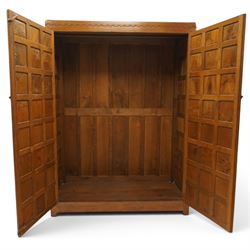 Mouseman - early-to-mid-20th century figured panelled and adzed double wardrobe of large proportions, the arcade carved cresting rail over two doors with adzed and figured oak panels, with wrought metal hinges and latch, relief carved mouse signature, the interior fitted with hanging rail, by the workshop of Robert Thompson, Kilburn