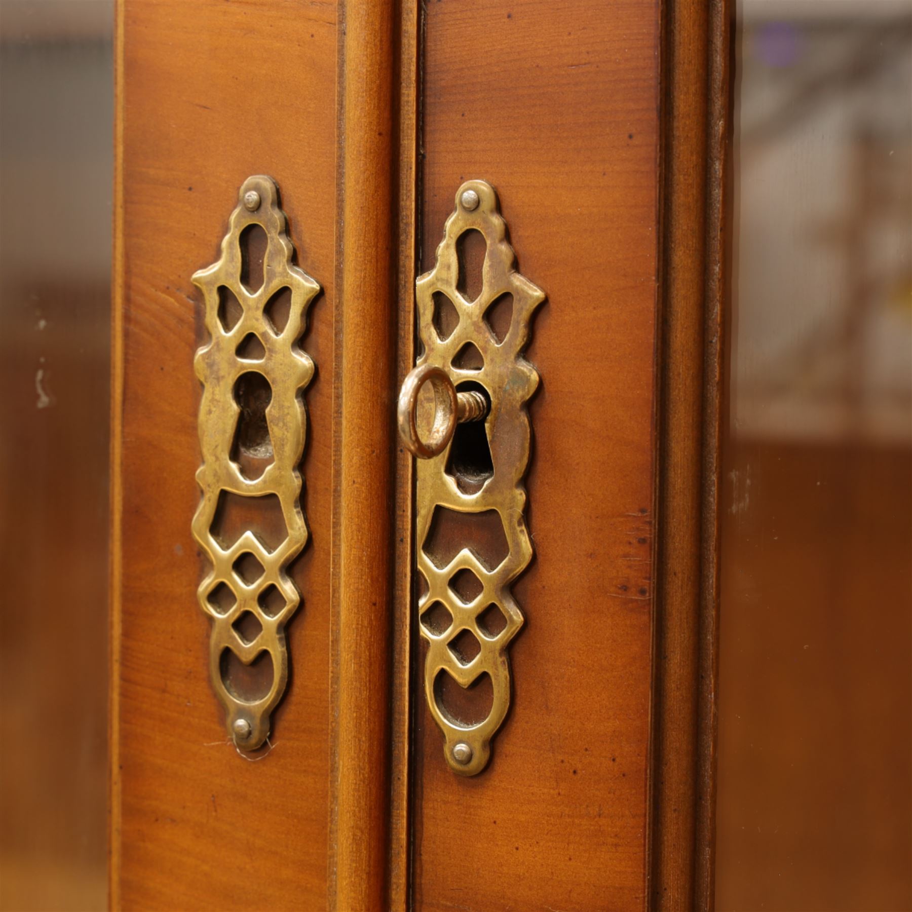 Edwardian mahogany bookcase cabinet, the moulded cornice above a pair of astragal glazed doors with gothic arched tracery, enclosing adjustable shelving, the projecting mid section fitted with two short drawers, over a pair of panelled cupboard doors with arched detailing, flanked by turned and pilasters, raised on a moulded plinth base