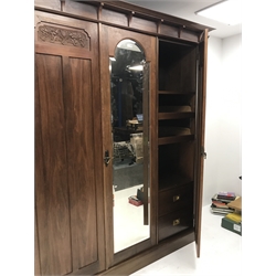 Irish Arts & Crafts walnut triple wardrobe circa 1908, projecting cornice above three doors enclosing fitted interior, single full length bevel edge mirror, platform base, W173cm, H204cm, D56cm