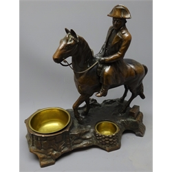  Smoker's stand as a bronzed spelter figure of Napoleon on horseback, the naturalistic base with two inset brass bowls and matchbox holder H30cm  