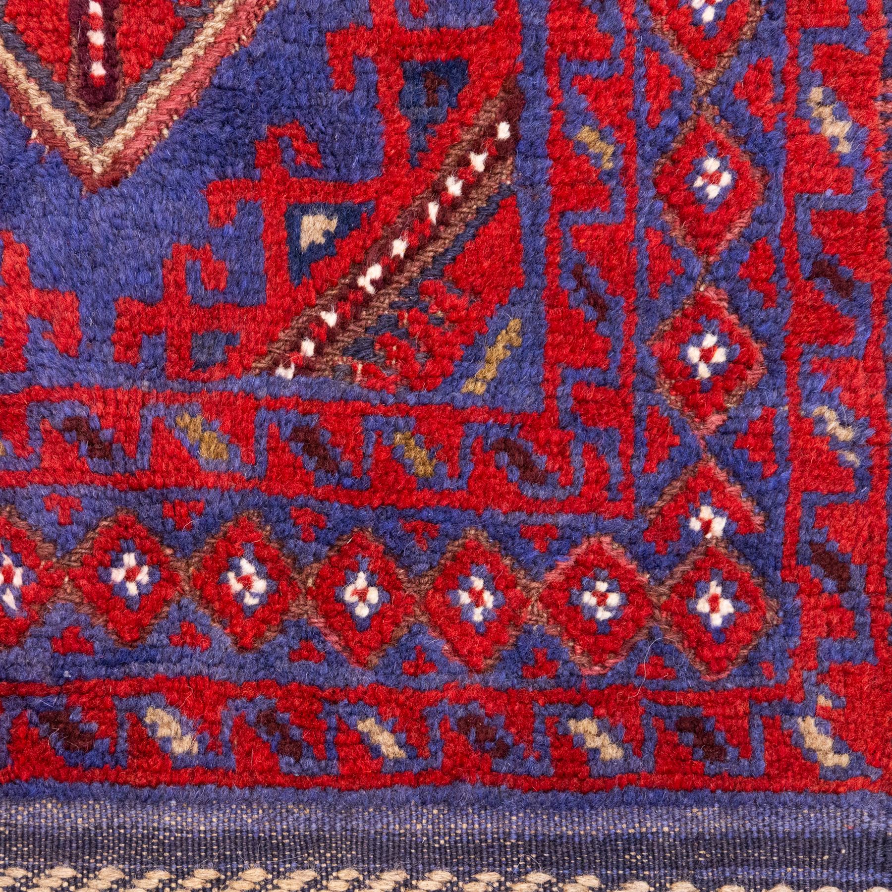 Afghan Meshwani runner, hand-knotted wool pile, indigo ground decorated with a vertical series of angular diamond medallions in tones of madder red, dark blue, framed by geometric borders with flatwoven kilim ends with fringe 