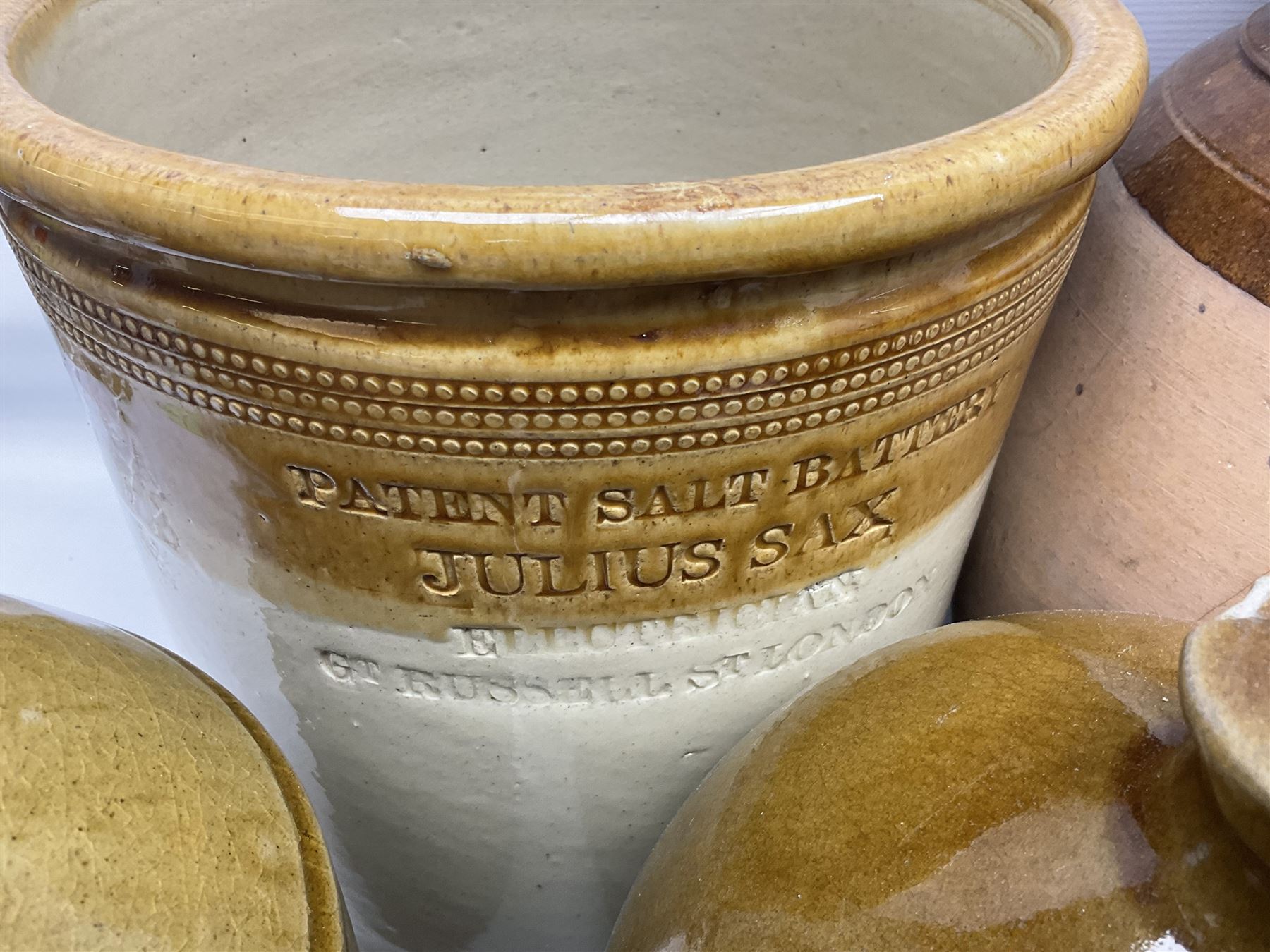 Quantity of stoneware flagons, to include Skipton, Clitheroe and Hellifield related examples, four salt glazed bottles, large cylindrical stoneware jar, large twin handled jar and vase, together with two brass jam pans, tallest H35cm