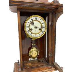 An early 20th century German wall clock with an 8-day HAC spring driven movement striking the hours on a coiled gong, in a mahogany case with a shaped pediment and turned columns flanking a full-length glazed door, with a two-part dial enamel with Roman numerals, minute track and pierced gothic designed hands, gridiron pendulum and beat plate. With Key.





