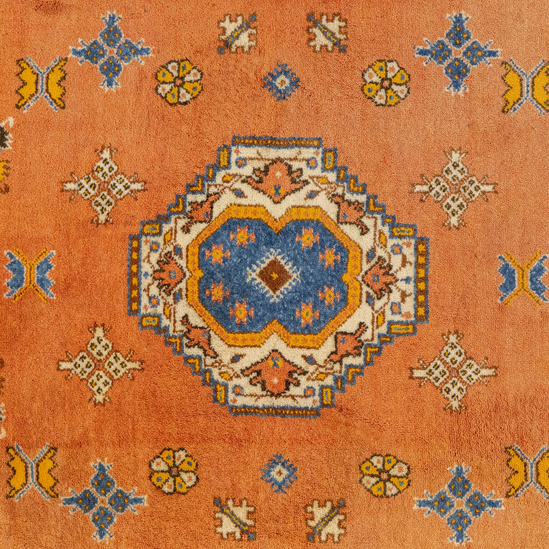 Turkish Anatolian hand-knotted carpet, salmon ground centred by a blue and cream octagonal medallion, scattered with geometric floral and tribal motifs, cream spandrels and yellow geometric border