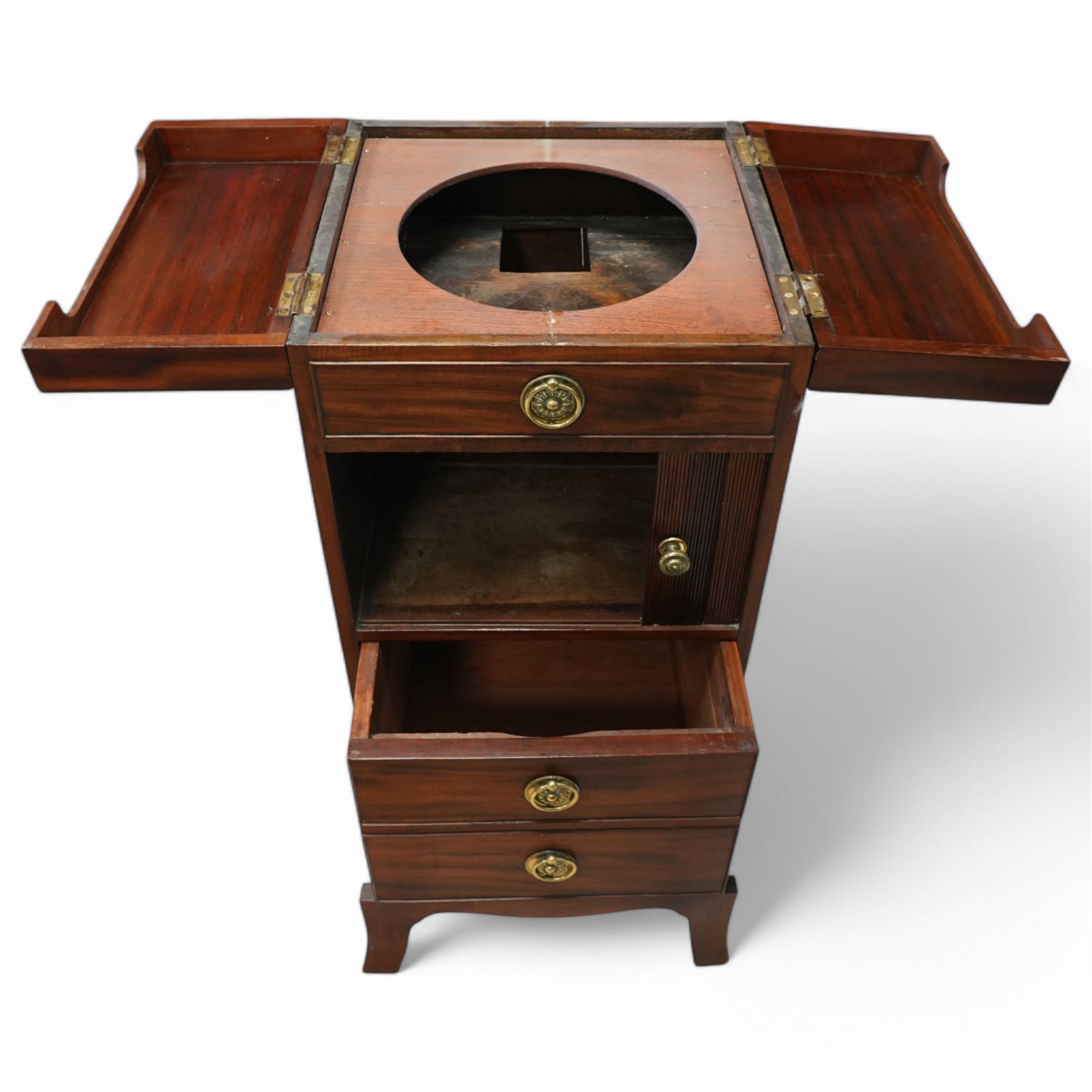 Early 19th century and later mahogany washstand, the dual-hinged fold-out top, over a cupboard enclosed by tambour roll, fitted with deep drawer to base disguised as two cock-beaded drawers, on splayed supports