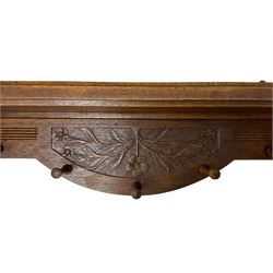 20th century oak wall hanging coat rack, relief carved with extending branches with flower heads, fitted with five turned hooks 