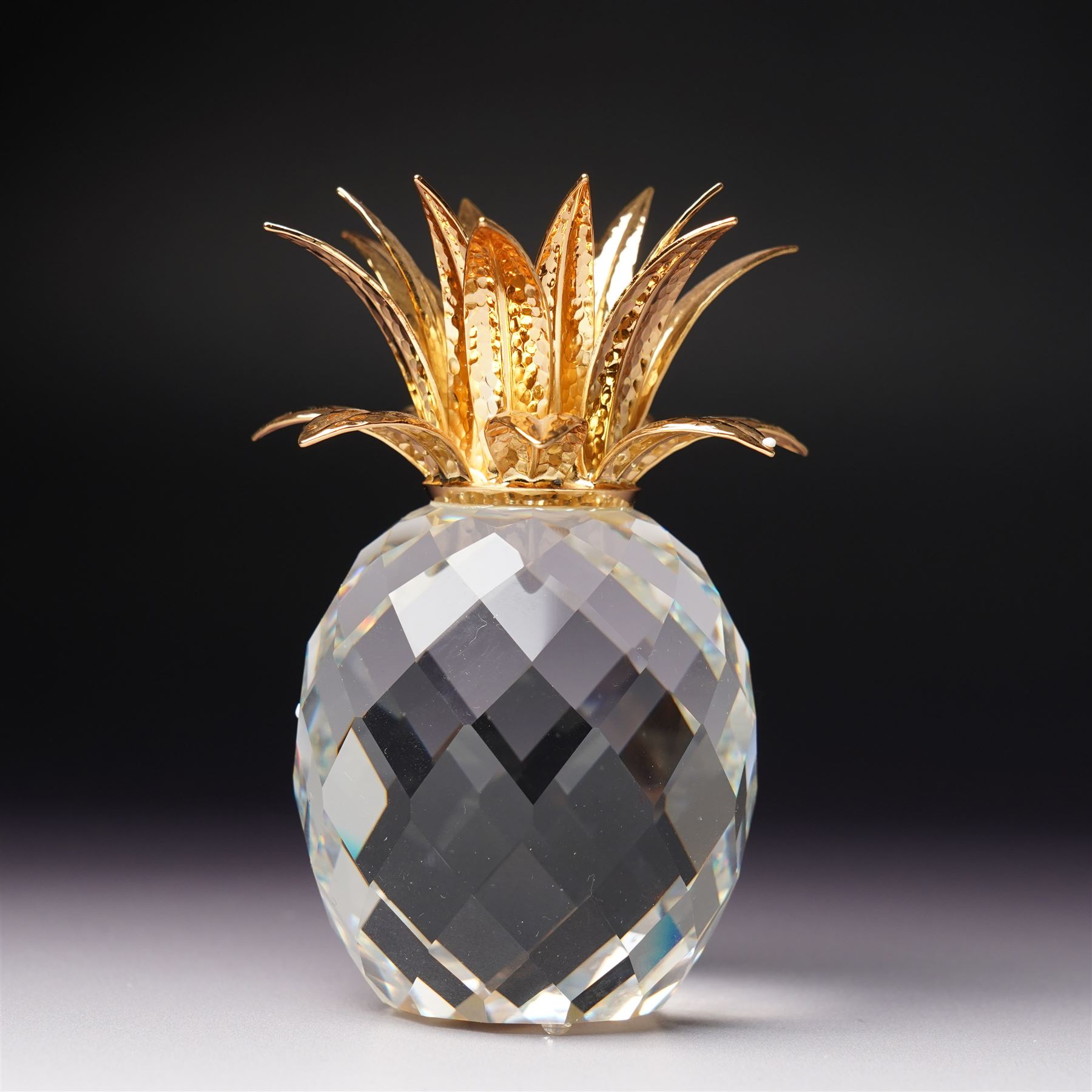 Pair of Swarovski Crystal candlesticks, boxed, together with two paperweights in the form of pineapples with gilt mounts, a large and small example, boxed (4)