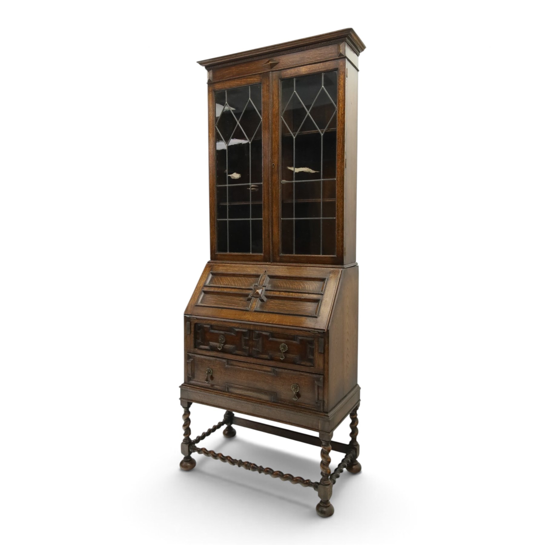 Early 20th century Jacobean Revival oak bureau-bookcase, astragal glazed doors enclosing two adjustable shelves, over geometric panelled fall-front enclosing fitted interior, over two drawers, raised on a spiral-turned base with barley-twist stretchers and compressed bun feet