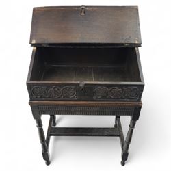 18th century carved oak Bible box on stand, the sloping lid with incised initials ‘MD’ and iron strap hinges, the front carved with stylised leaf and scroll panels enclosing central iron lockplate, on stand with gadrooned frieze, turned legs and plain stretchers
