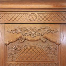 Early 20th century French oak triple door armoire, the moulded top above a frieze with carved lozenge decoration and central rosette, the central mirrored door enclosed by carved surround with floral crest, flanked by panelled doors with lattice carving, the base with shaped apron centred by carved basket motif, upon shaped cabriole supports