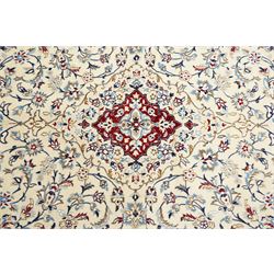 Central Persian Nain hand-knotted rug, ivory field with central medallion in tones of indigo and blue, issuing vinery, palmettes and floral sprays with conforming spandrels, dark blue main border of floral vinery and stylized palmettes, framed by multiple guard borders, with cotton fringe ends 