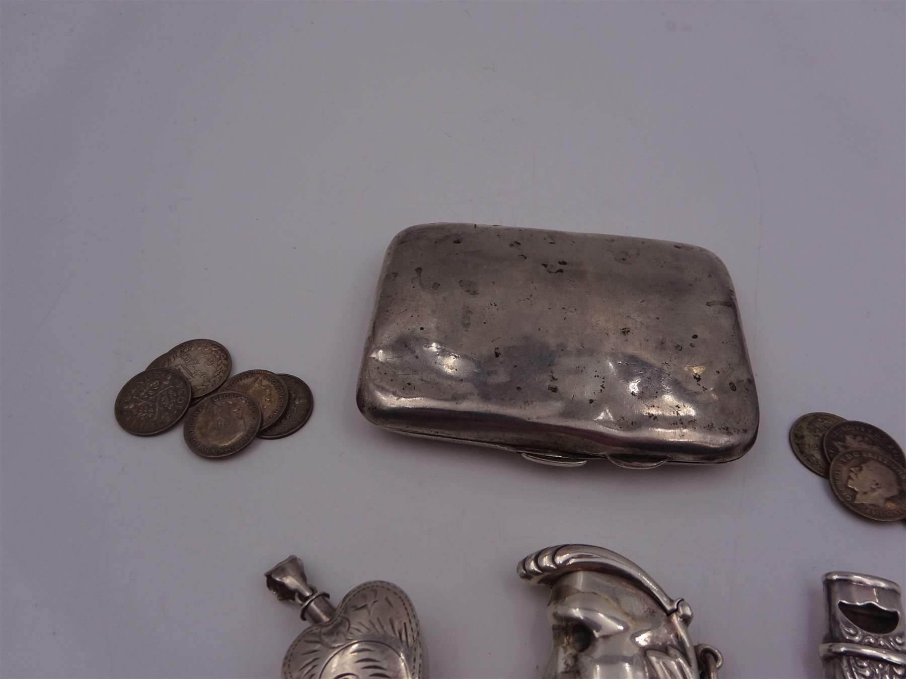 Group of novelty silver items, comprising man in the moon vesta case, perfume pendant and a whistle, unmarked but test silver, together with a mother of pearl handled silver fruit knife, silver cigarette case, both hallmarked and a small quantity of silver threepences