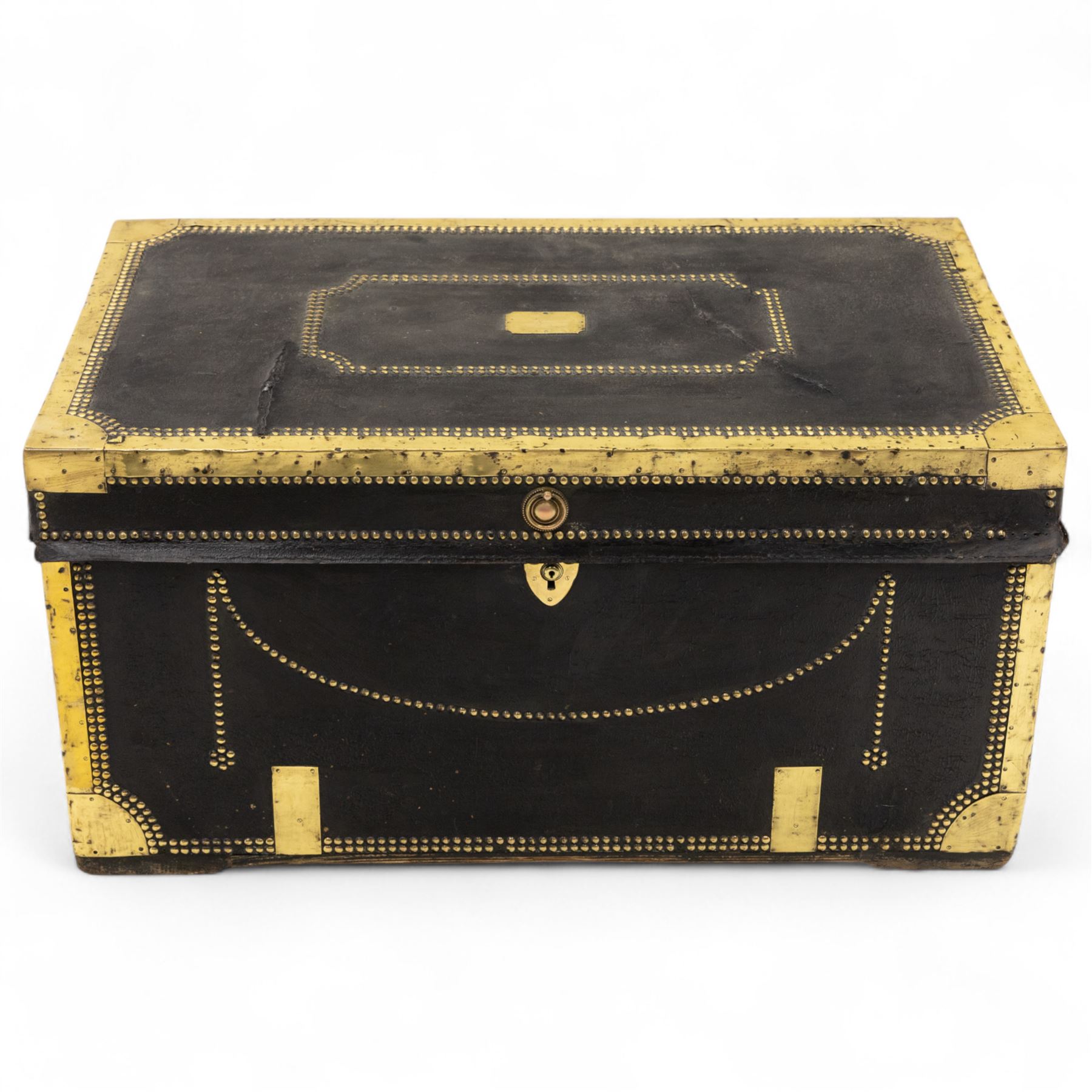 An early 19th-century Georgian brass-bound travelling trunk, leather-covered exterior with brass stud work decoration, front with central brass lock plate, hinged lid with camphor wood interior, external sides fitted with large brass carrying handles 