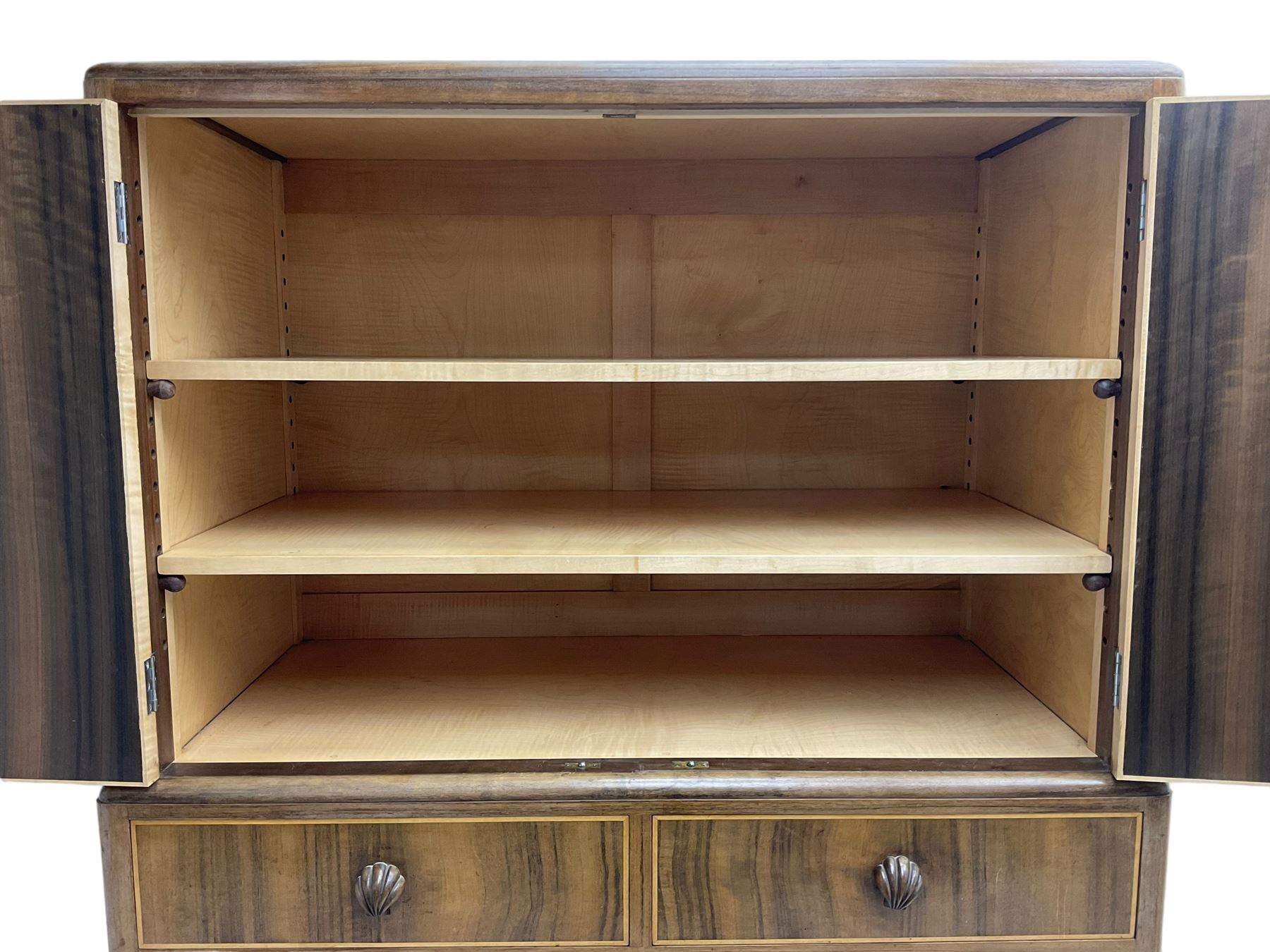 Early 20th century Art Deco walnut cocktail tallboy chest, fitted with double cupboard enclosing two shelves over two short and three long drawers, each with shell shaped handes