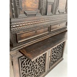 18th century and later carved campaign chest on cupboard, the top section with projecting cornice over two doors with raised geometric mouldings, incised carved decoration throughout, two drawers, fitted with carrying handles, the lower section fitted with slide above cupboard enclosed by two fretwork panelled doors