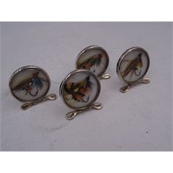 Set of four early 20th century silver mounted place card holders, each of circular form and set with a coloured fly fishing hook behind a glazed panel, upon three pad feet, hallmarked Grey & Co, Chester 1912, H4.5cm, contained within red fitted case, with purple silk and velvet interior