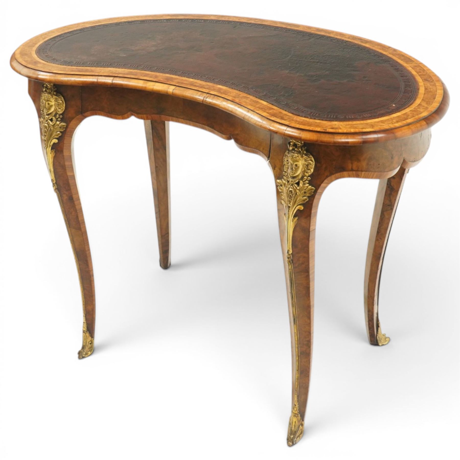 Gillow & Company (1862-1897) - Victorian figured walnut kidney shaped writing table, the shaped top inset with oxblood leather writing surface with embossed edge, surrounded by banded burr-walnut and crossbanding with moulded edge, fitted with single shaped frieze drawer flanked by scalloped side-aprons, raised on tapering and chamfered cabriole supports embellished with ormolu mounts in the forms of maidens over tapering acanthus leaves, the mounts trailing down the front of the legs to terminate to ormolu scroll feet, stamped 'Gillow & Co 3576' to drawer interior