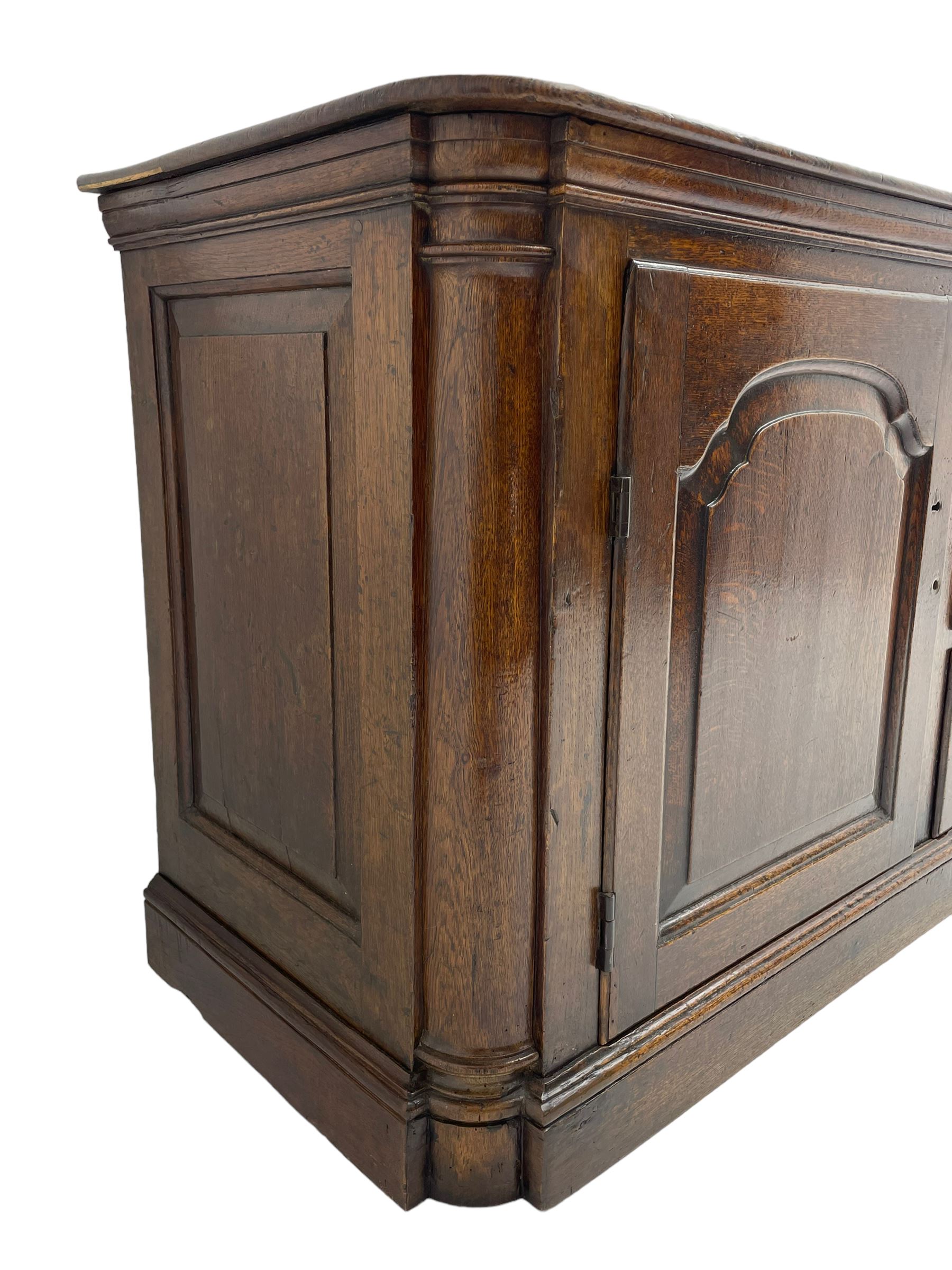 George III oak dresser base, rectangular top with rounded corners over moulded frieze rail, canted corners with turned quarter columns, fitted with three drawers with moulded edges flanked by two cupboards, enclosed by ogee arched fielded panelled doors, panelled sides, moulded plinth base