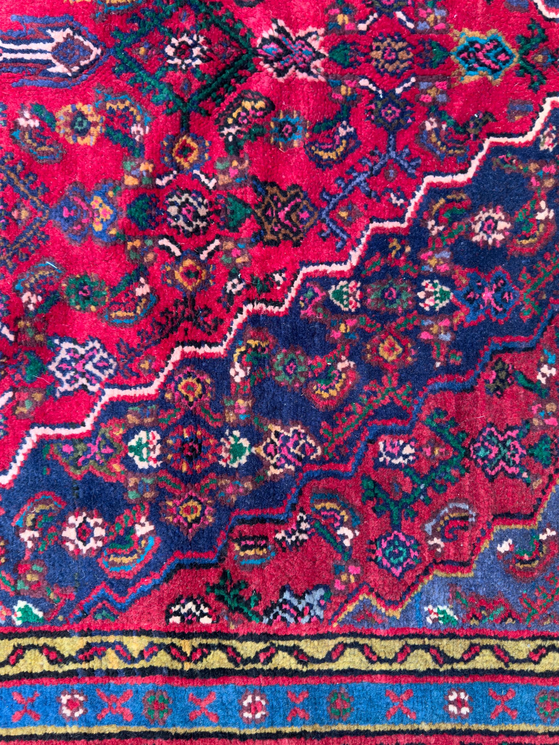 Northwestern Persian Hamadan hand-knotted rug, madder red field with a lozenge medallion enclosing an ivory centrepiece, indigo spandrels within an ivory border of stylized floral motifs between multiple guard borders 