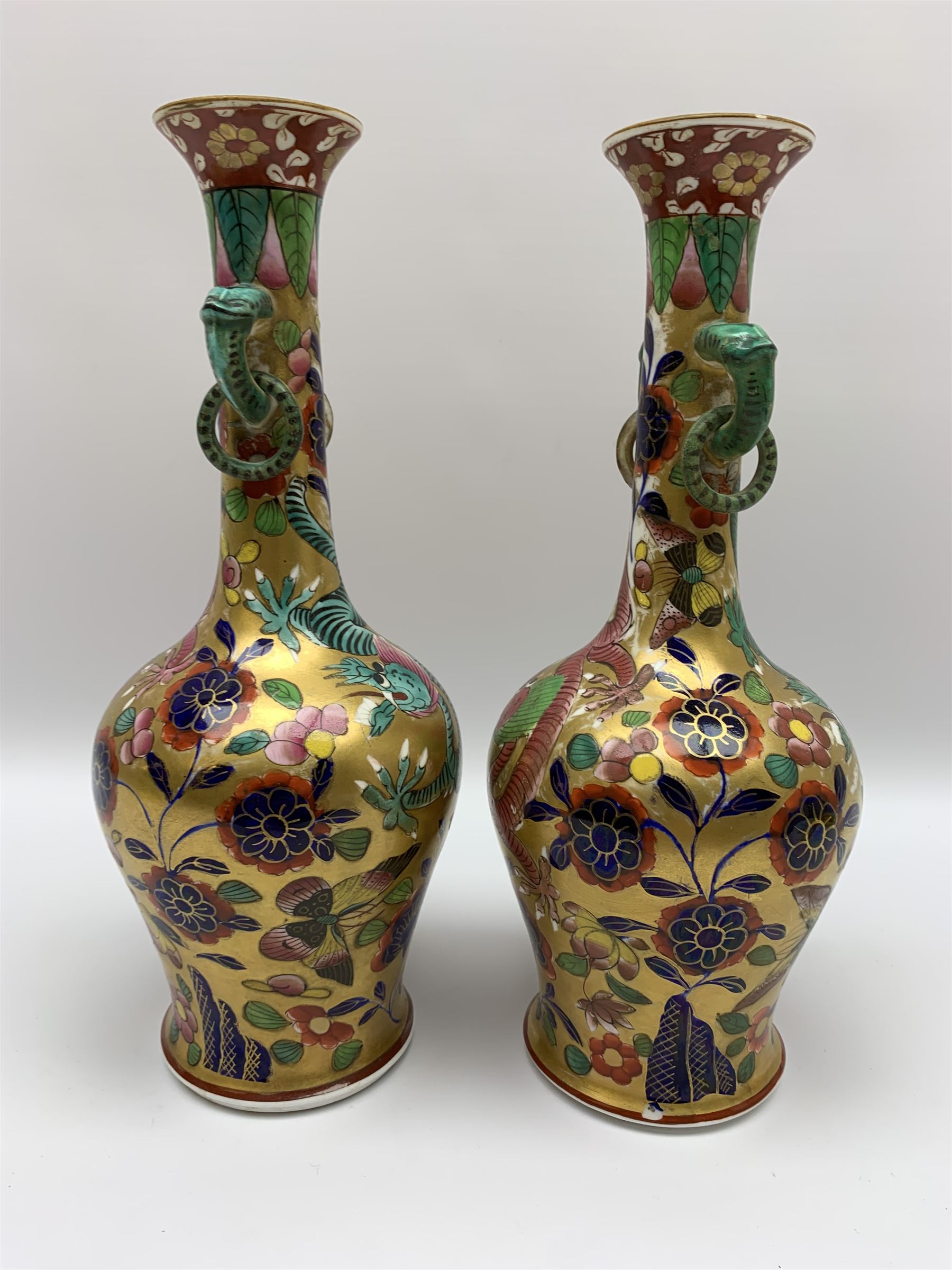 Pair of early 19th century Miles Mason vases, the baluster bodies with tall slender necks supporting twin stylised trunk handles with rings, decorated with Chinese dragons, butterflies, and blossoming flowers against a gilt ground, with spurious Chinese marks beneath in iron red, H27.5cm