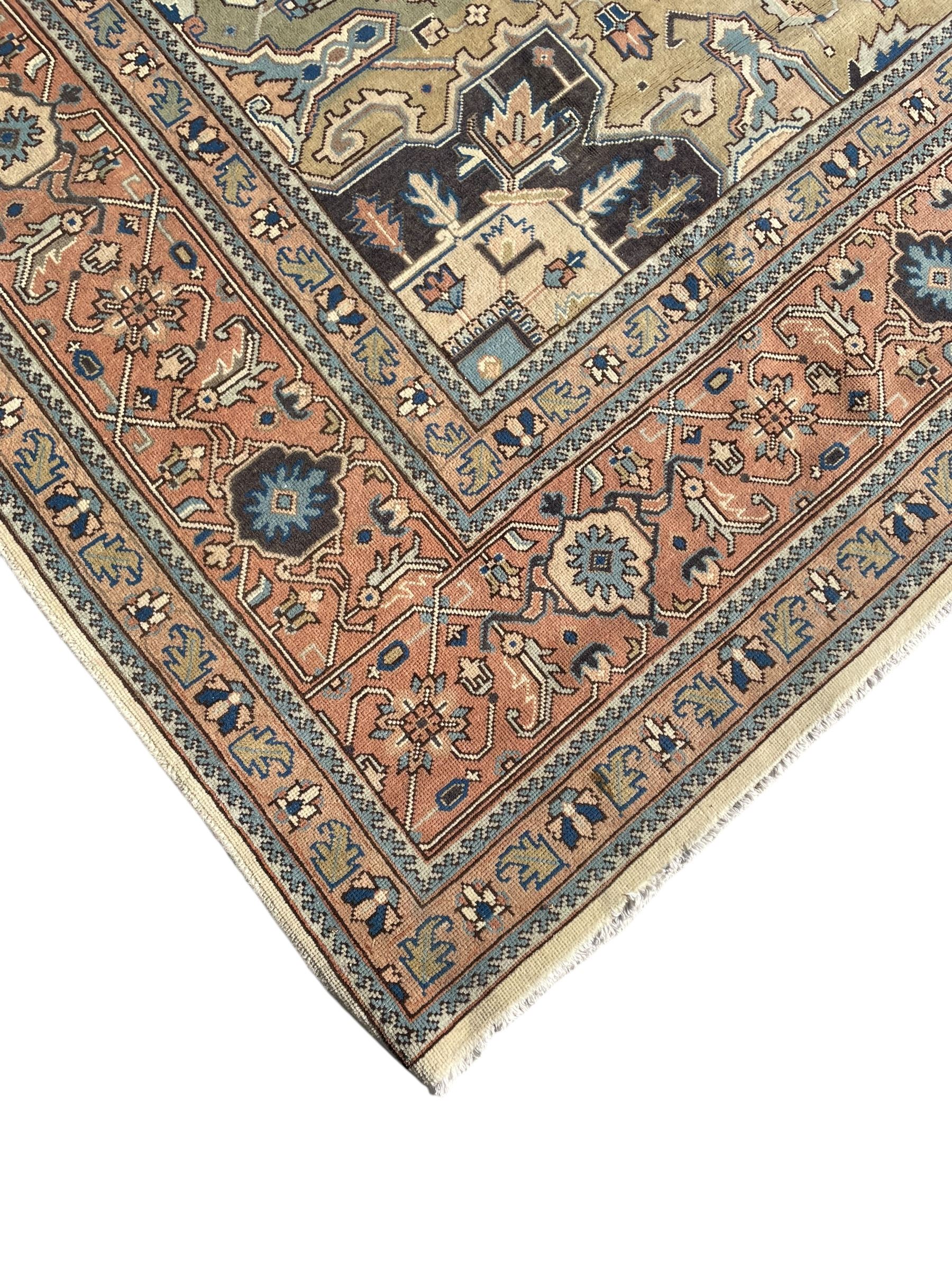 Persian Heriz pale olive and ivory ground carpet, large quatrefoil medallion with palmettes, the surrounding field decorated with trailing leafy branches and stylised plant motifs, peach ground borders with overall floral pattern, within guard stripes 