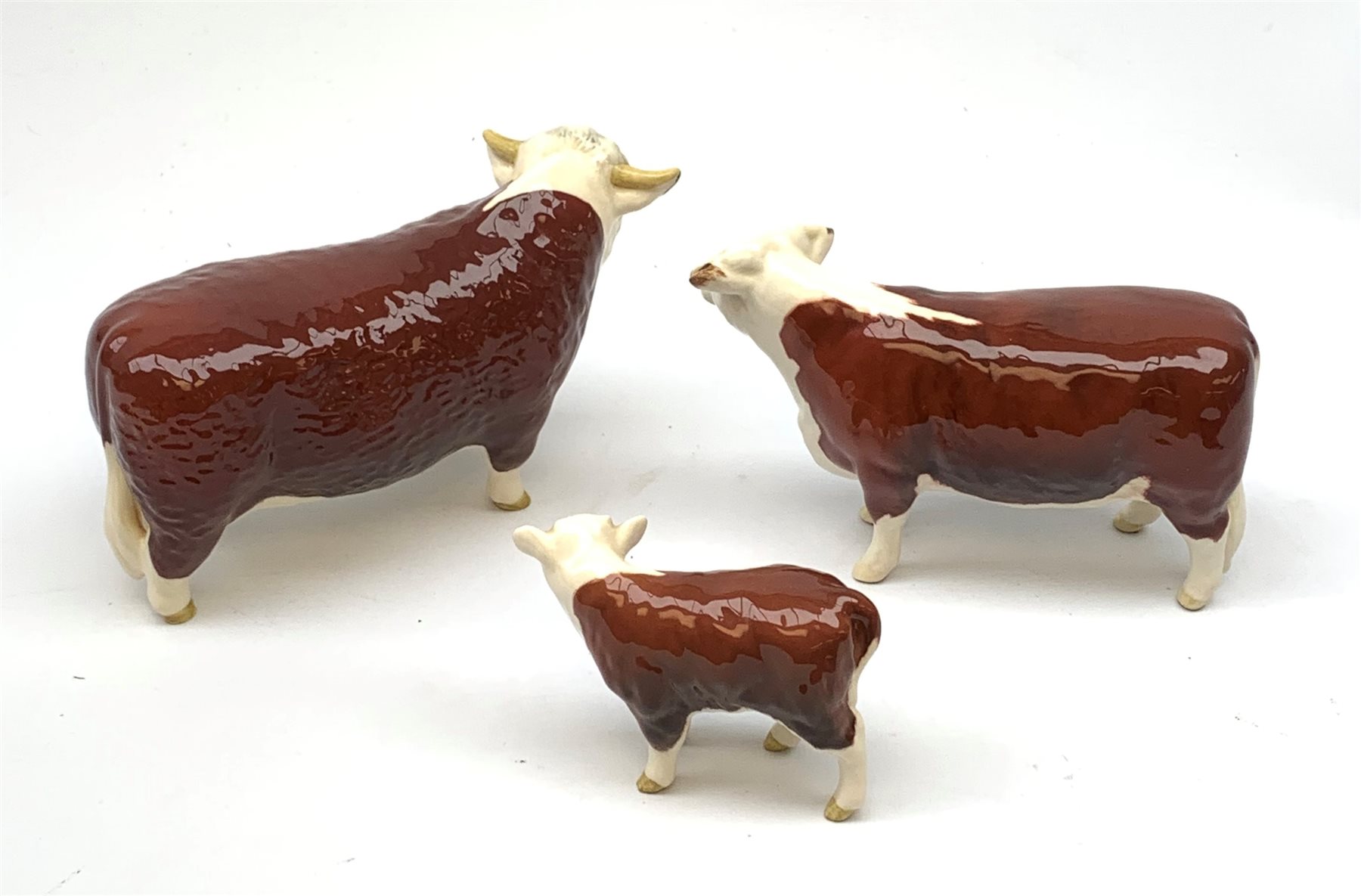 A Beswick Hereford Bull, Hereford Cow, and Hereford Calf, each with printed mark beneath, Bull and Cow marked CH of Champions. 