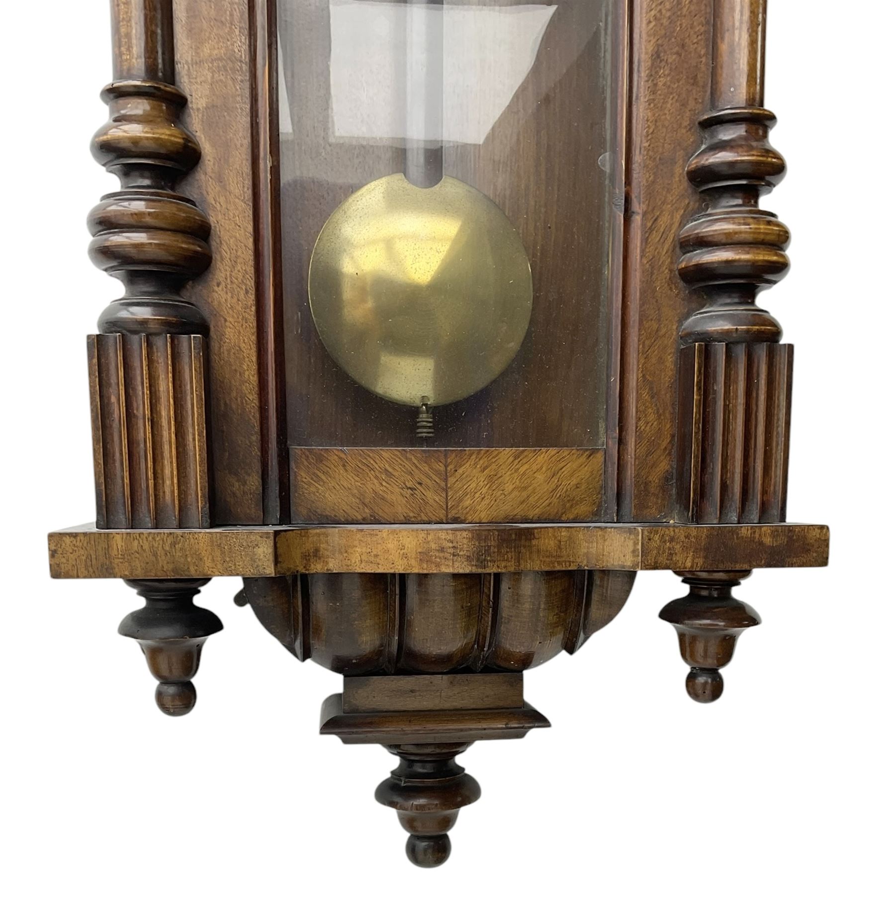 German- Late 19th century 8-day spring driven wall clock in a walnut and ebonised case, with a broken pediment and turned finials, fully glazed door with a visible pendulum and two part ivorine dial, chapter with roman numerals and minute track, rack striking movement sounding the hours and half hours on a coiled gong. With key .