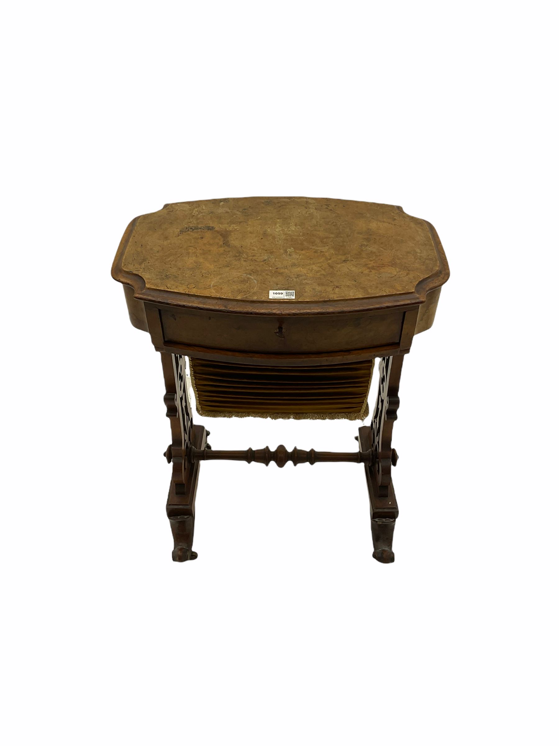 Victorian figured walnut work table, the shaped moulded top over single drawer and upholstered bag, shaped end supports with pierced decoration joined by turned stretcher, splay scroll carved supports