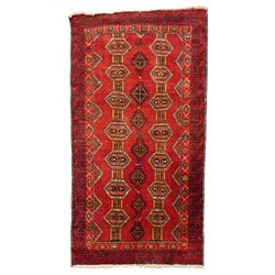 Persian Baluchi crimson ground rug, decorated with three columns of geomtric motifs