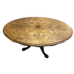 Victorian walnut loo table, oval tilt-top with quarter matched veneers and moulded edge, on turned column with three splayed supports, each carved with flower heads