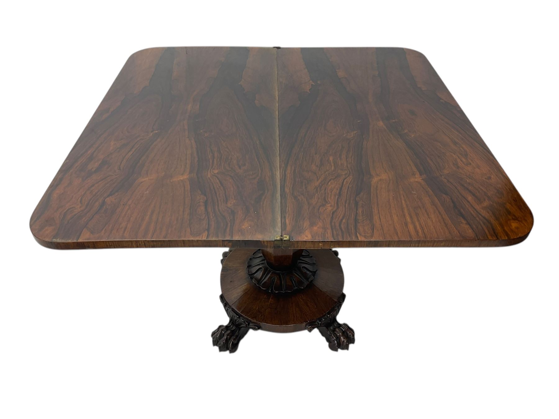 Victorian mahogany tea table, rectangular top with rounded corners, folding and swivelling to reveal interior surface, supported on a faceted baluster-shaped column, raised on a circular platform base with carved acanthus details, ending in four lion paw feet
