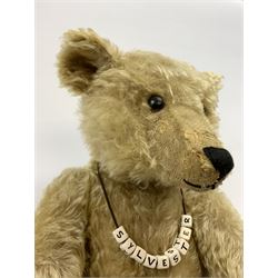 Early 20th century German Steiff large teddy bear c1907 with FF button to left ear, with wood wool filled blonde mohair body with humped back, the swivel jointed head with black boot button eyes, pronounced clipped muzzle and black vertically stitched nose and mouth and jointed elongated limbs with long arms and felt paw pads with black stitched claws, known as 'Sylvester' H24