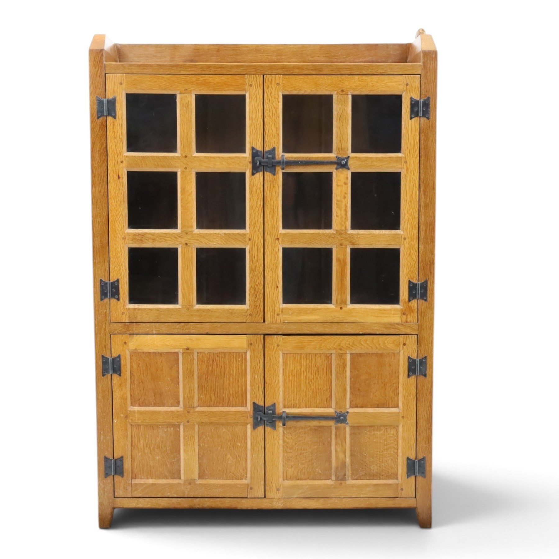 Rabbitman - oak glazed bookcase or display cabinet, lightly adzed rectangular top with raised gallery, twin glazed doors enclosing two shelves, over a pair of panelled cabinet doors with wrought iron fittings, with carved rabbit signature, by Peter Heap of Wetwang