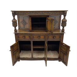 20th century carved oak court cupboard, s-scroll carved frieze over panelled cupboard door carved with arch, lobe and scroll carved cup and cover supports, fitted with three drawers and three cupboards below