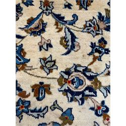 Persian Kashan ivory ground rug, the field decorated with stylised plant motifs and interlacing leafy branches, scrolling border decorated with further plant motifs, floral design guard bands  